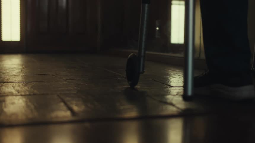 A persons legs are visible walking beside a walker resting on a polished floor