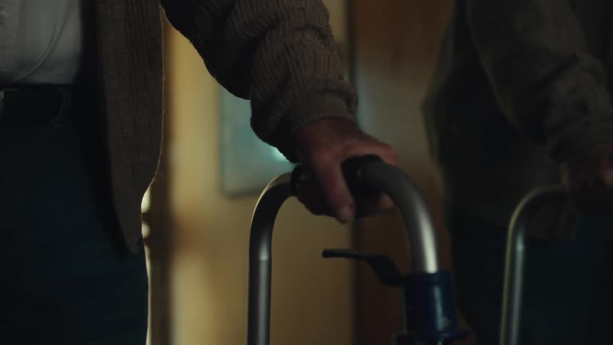 Mirror reflects an elderly man walking with a walker