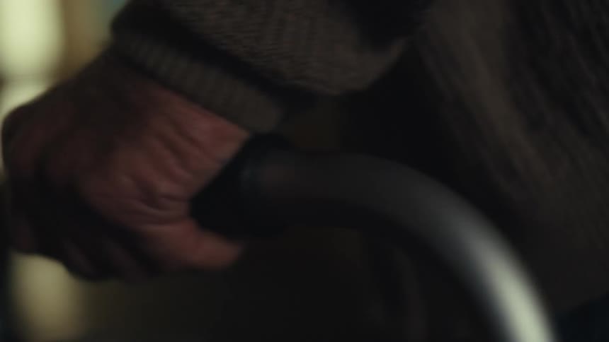Close up of an elderly mans hands walking on a metal walker towards a door