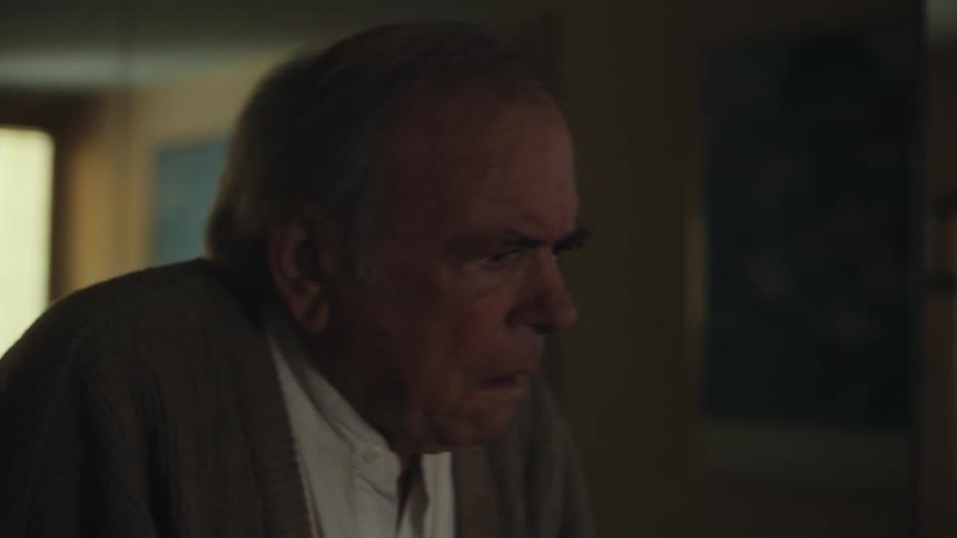 Weak elderly man walking with a walker down the hallway in the house
