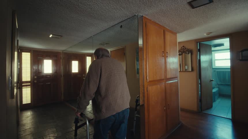 Elderly man with a walker walking to the door