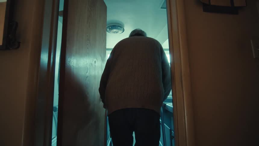 Elderly man using a walker walking towards the bathroom