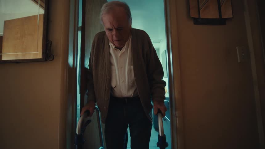 Elderly man opening the door and leaving the bathroom with the help of a walker