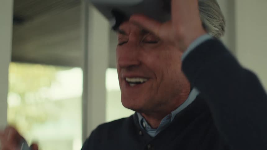 Man standing up wearing a vr headset punching in the air and smiling indoors during daytime