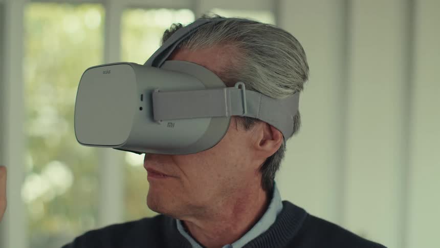 A man puts on a virtual reality headset and starts playing a video game