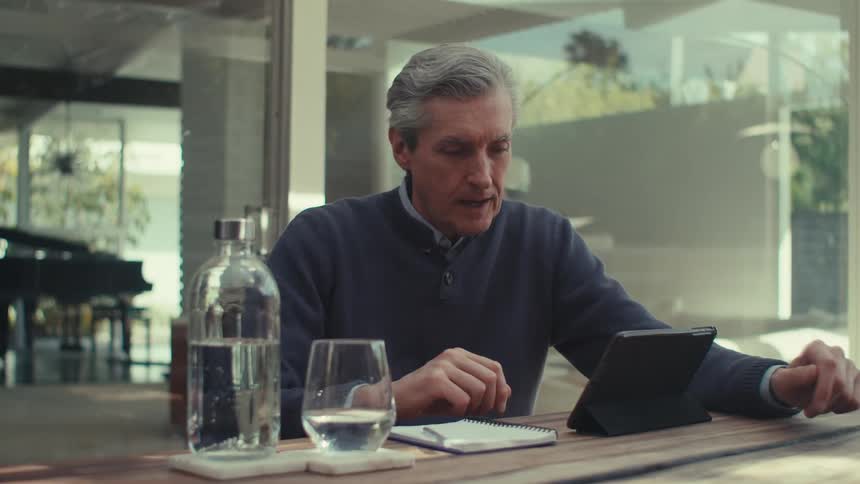 Man sitting at a table talking on a tablet