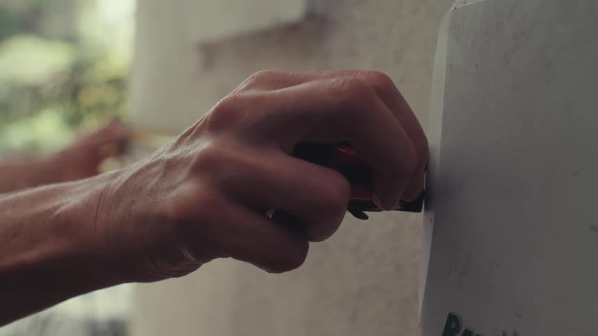 Male worker takes measurements on the exterior wall of a residential building