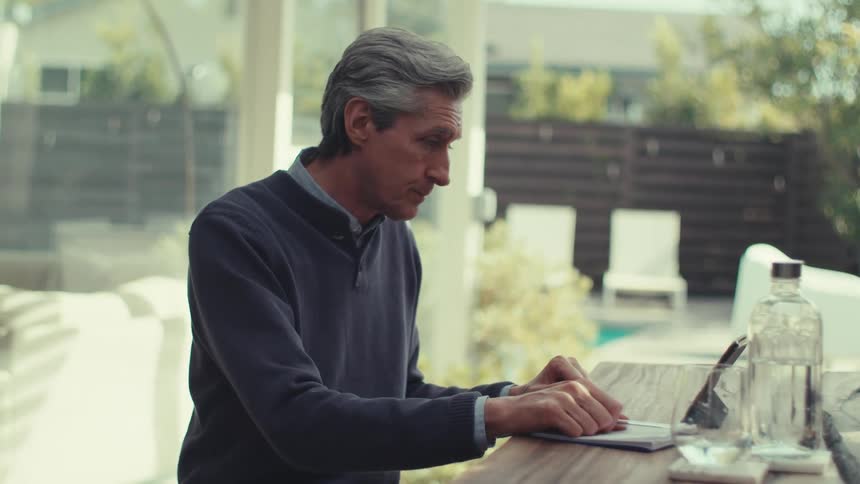 A man waves and ends a conversation on his tablet