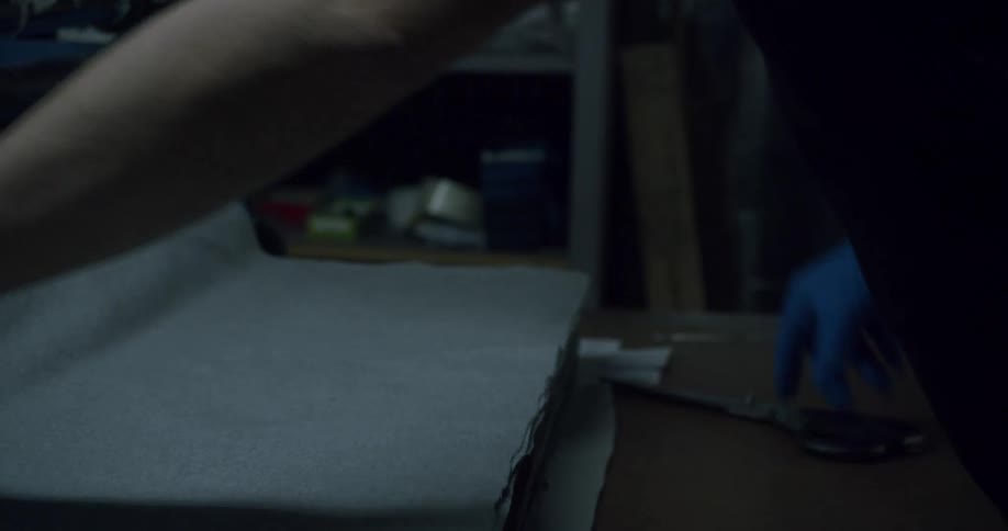 Gloved hands working with gray fabric