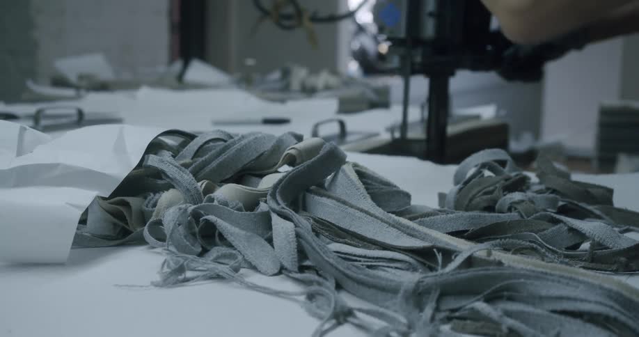 Gloved hands handling a machine and fabrics on a table