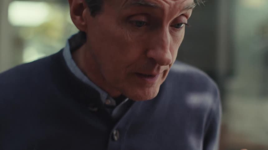 Man sitting at a table talking making hand gestures
