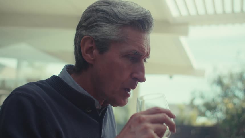Man sitting talking and drinking a glass of water