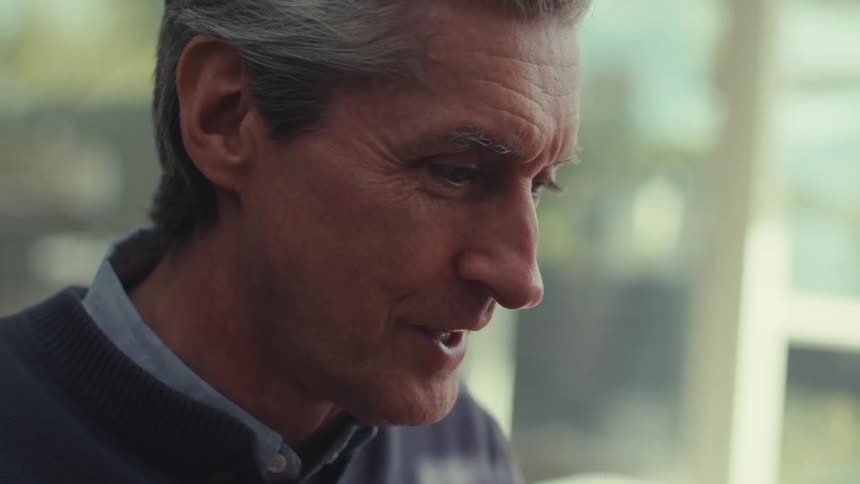 A man touches his face while he talks
