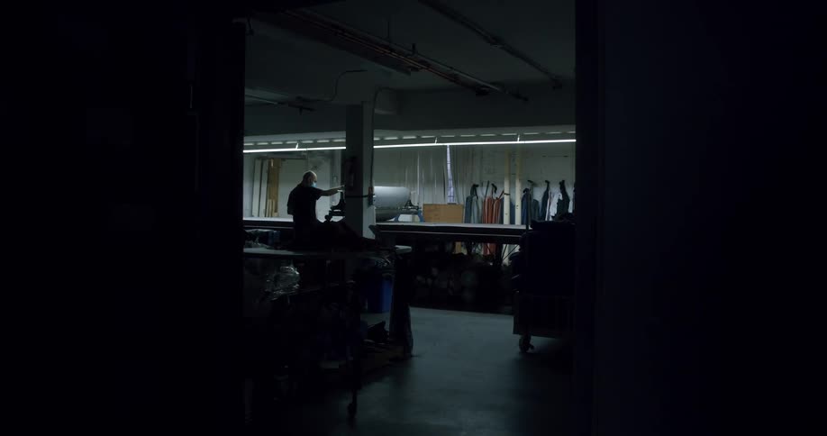 Man uses a large machine in a dimly lit workshop