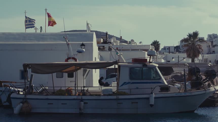 White boat docked next to a building with a city and a hill on the background outdoors during daytime