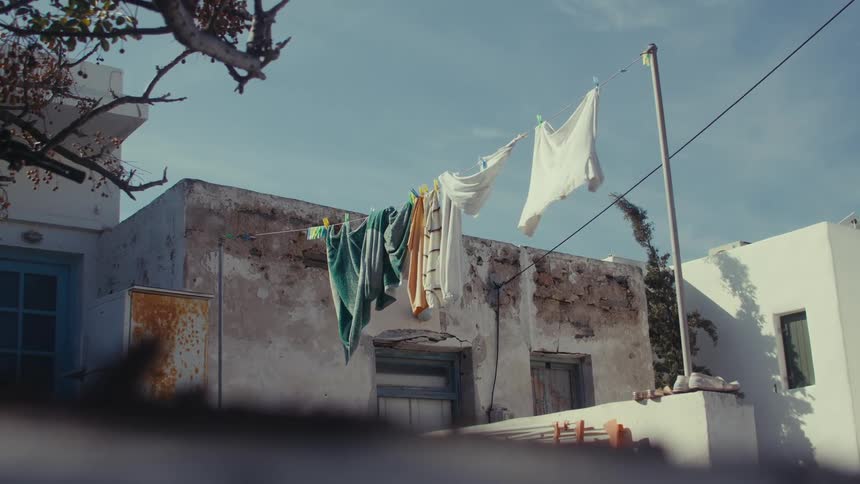 Laundry hangs on a clothesline in front of a weathered whitewashed building