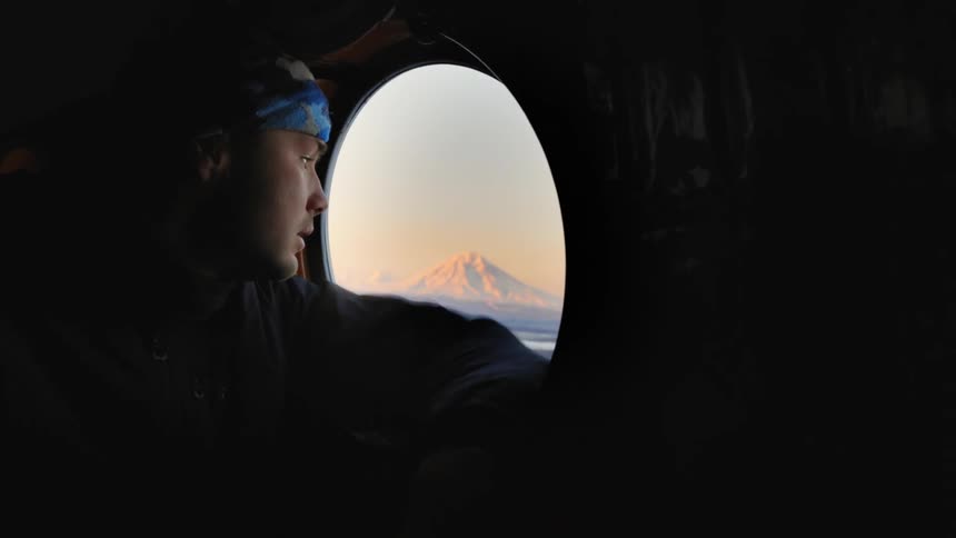 A man flying in a plane is looking out the window