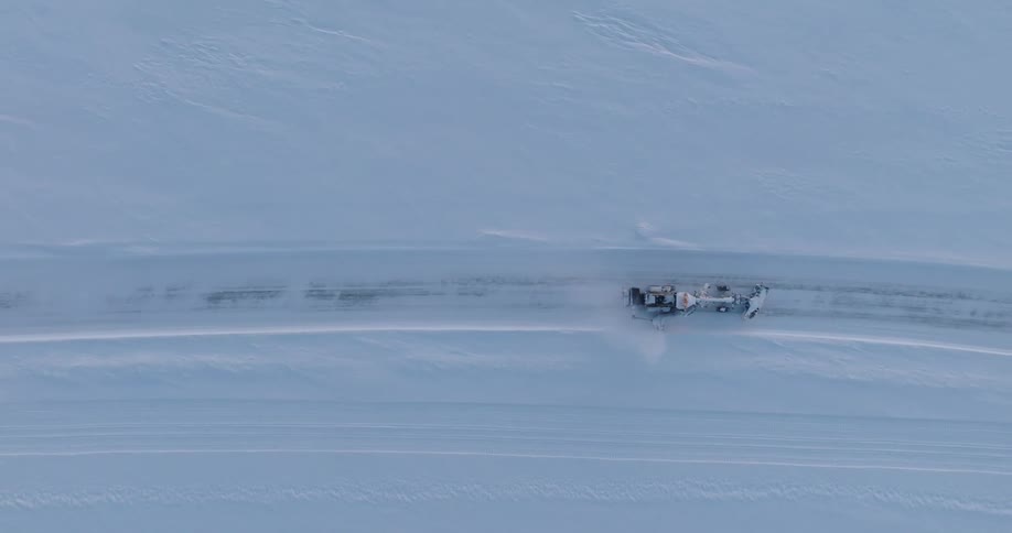 Aerial view of a snowplow is clearing a road through a vast snowcovered landscape