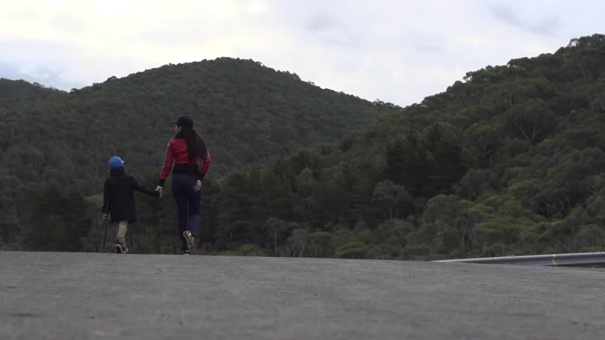 Woman and child walk down road together