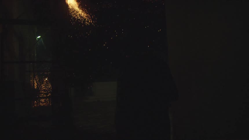 Sparks falling between buildings at night