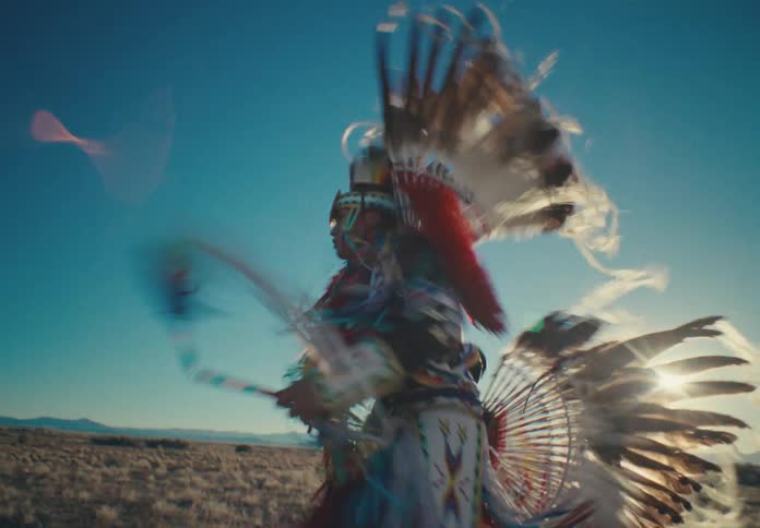 Man wearing traditional native american clothing and dancing in a desert landscape