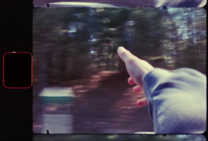 A film clip of a persons hand stretched out through the window of a car