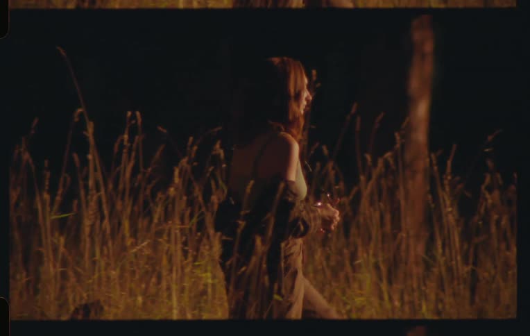Woman walking through a field and using a camera