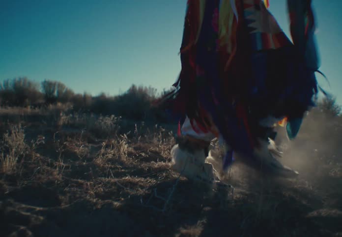 Legs of a person in a tribal covering dancing through undergrowth