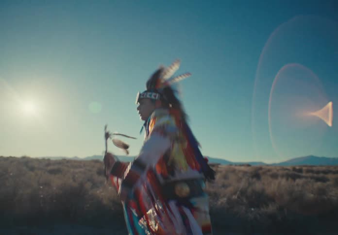 Native american man in ceremonial attire dancing amid a desert landscape