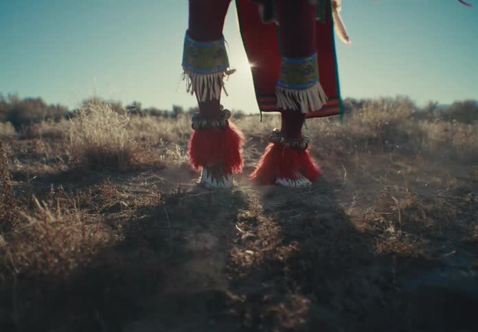 Legs of a person in traditional dress tap dancing in a natural setting