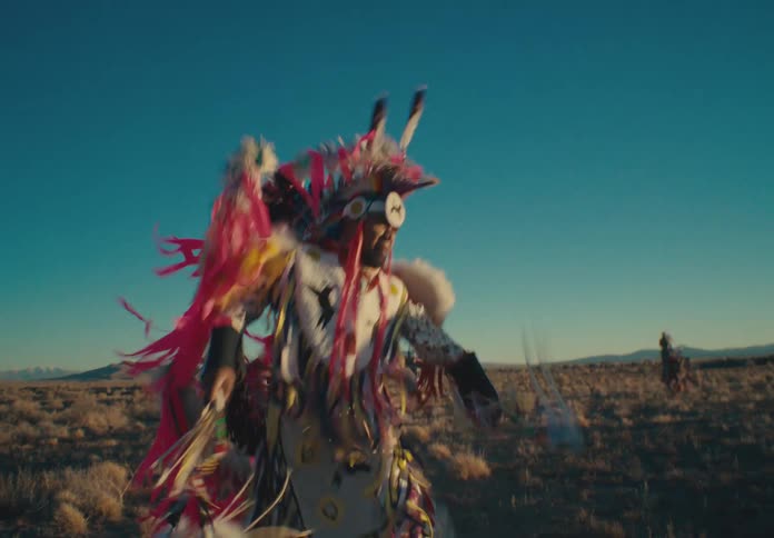 Group of native american people wearing tribal costumes dancing in a field