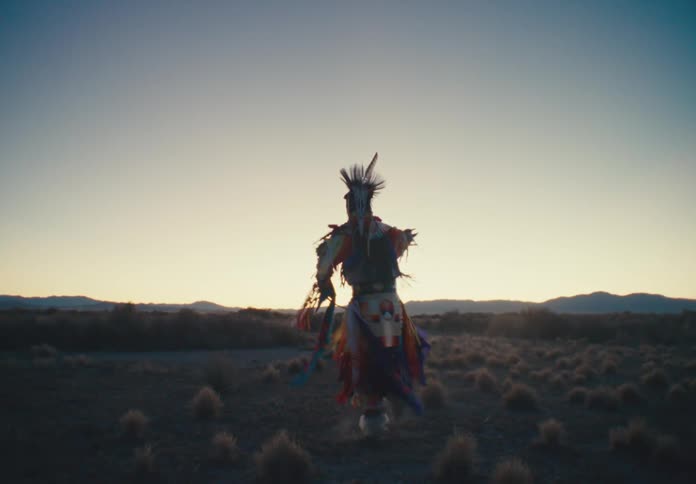 Person in native american costume of a tribe dancing in a field in a morning