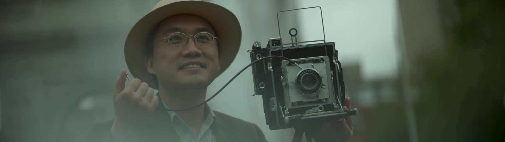 A man smiles while using an old camera
