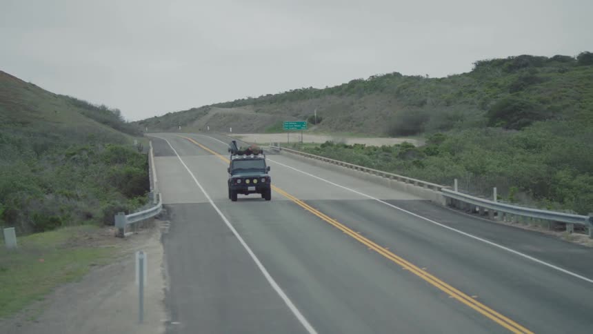 Car driving down an empty road on a cloudy day