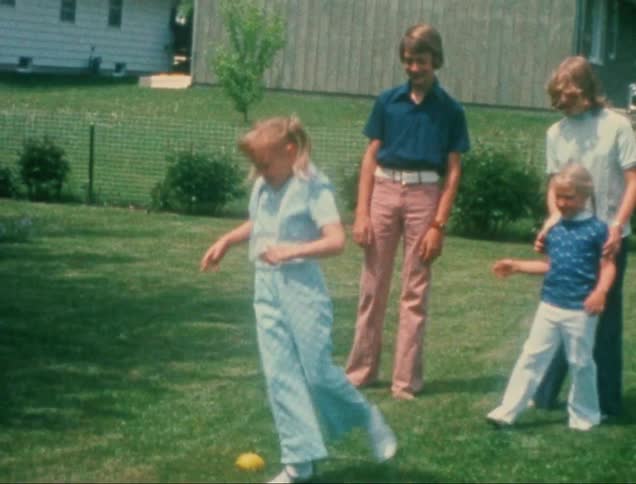 Children are playing outside on a grassy lawn near a house