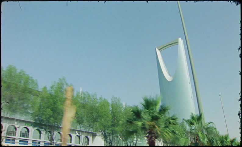 The kingdom centre tower in riyadh saudi arabia with its distinctive inverted arch design surrounded by palm trees