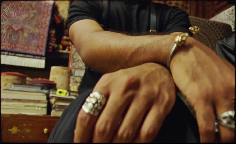 Closeup of two hands adorned with large ornate rings and a bracelet
