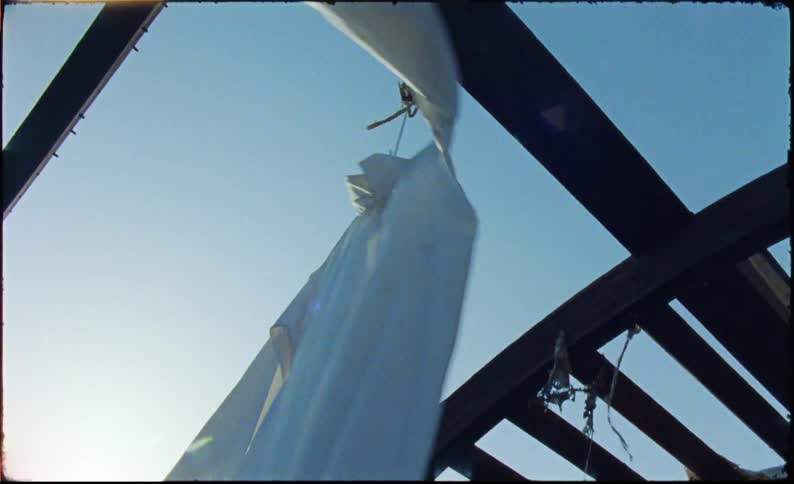 White long sleeve shirt hanging by a rope on a wooden structure
