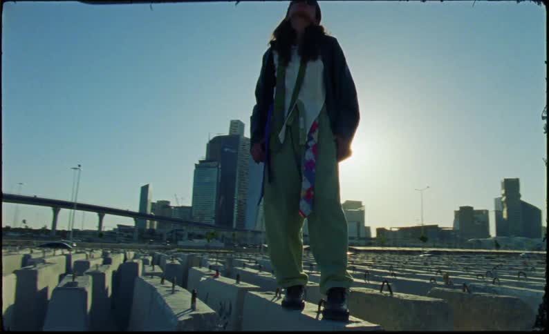 A young woman is standing on a construction barrier and posing before walking on a row of them