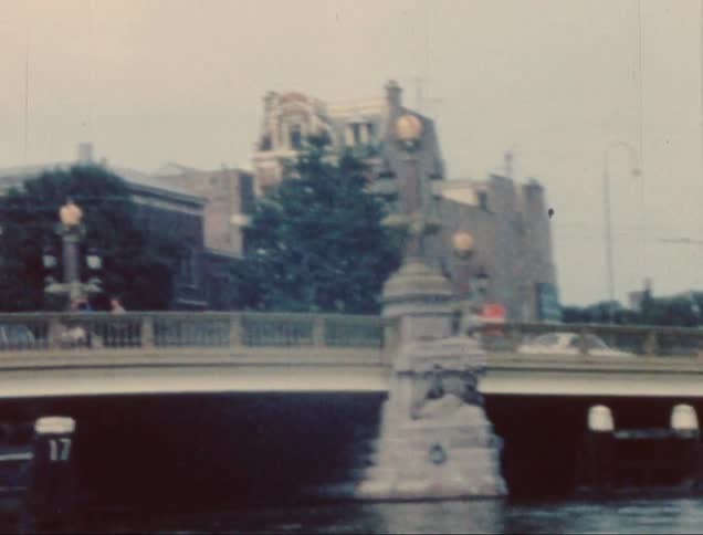 Cars driving over a bridge over water on the outskirts of a city
