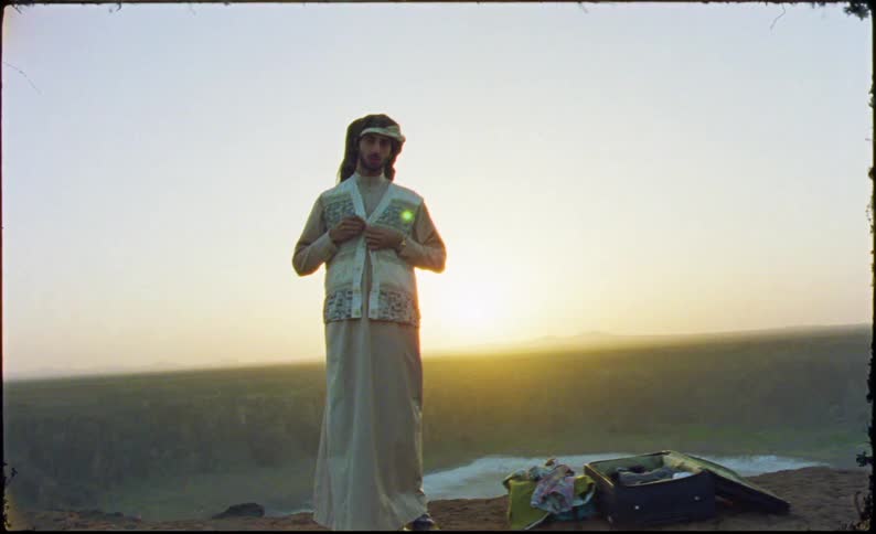 Man standing on high ground during sunset adjusting his shirt