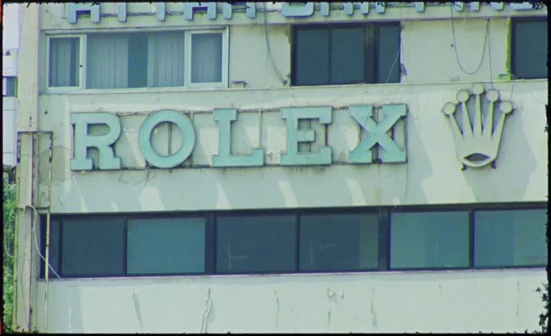 A building with faded signs advertising attar shipping agency and rolex with a crown logo suggesting a mix of businesses in the area
