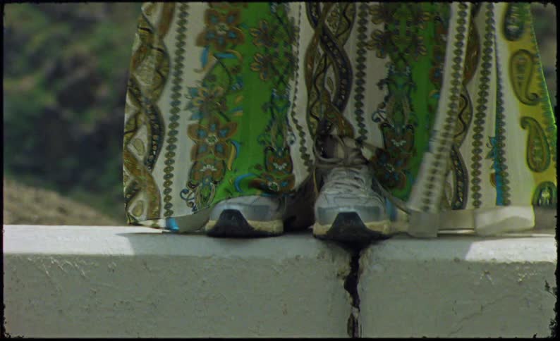 Feet of a person on top of a concrete block wearing a long greenish dress