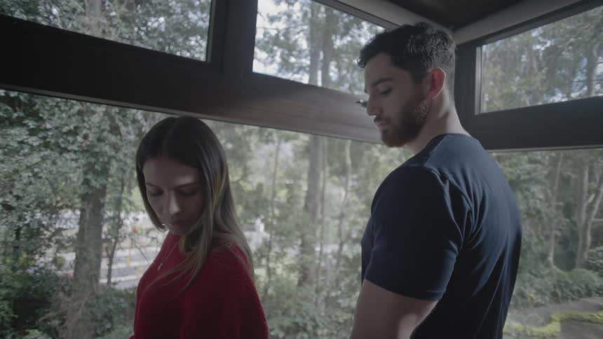 Man and woman in a sun room look at the trees outside and then around the room