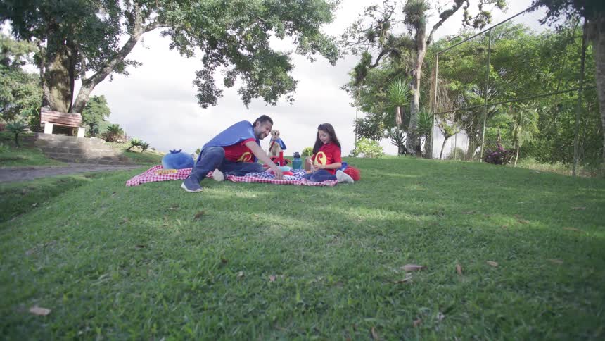Father with his daughter on a picnic in a garden and a dog in the background