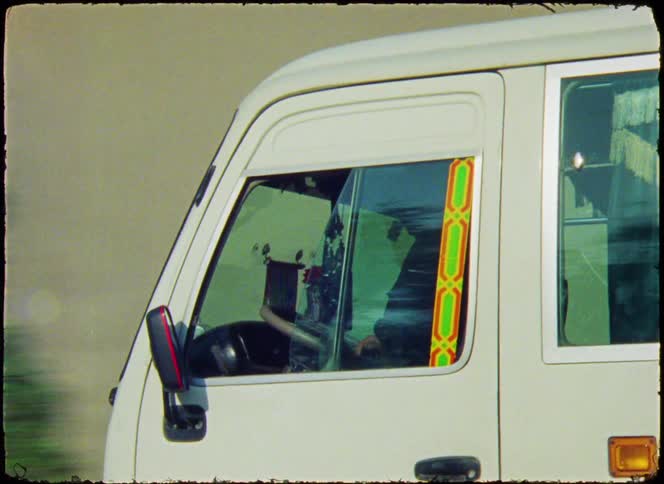 A white vehicle with a decorated window frame is shown from the side focusing on the drivers seat and side mirror