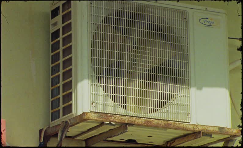 An air conditioner is mounted on the side of the building