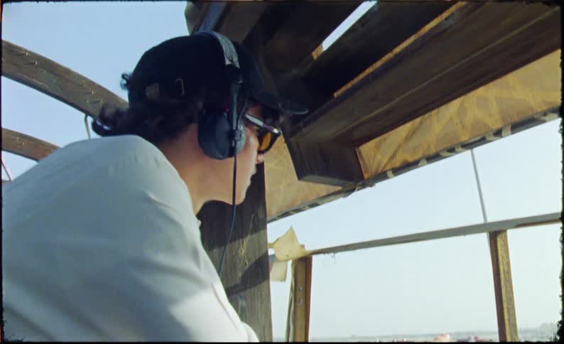 Man puts headphones on and leans against a halfwall in a partially completed building