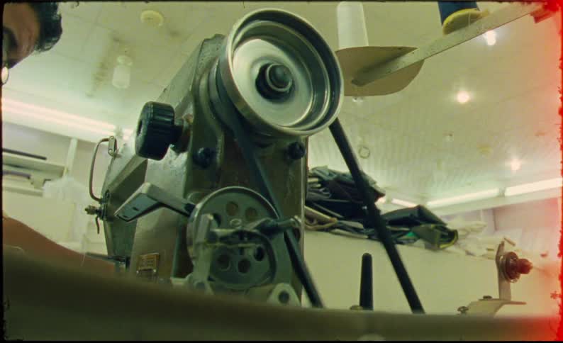 Man sews using an industrial machine in a well illuminated workshop