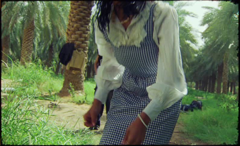 Man waits while female model adjusts her hair before he heads towards jackets hanging on a palm tree